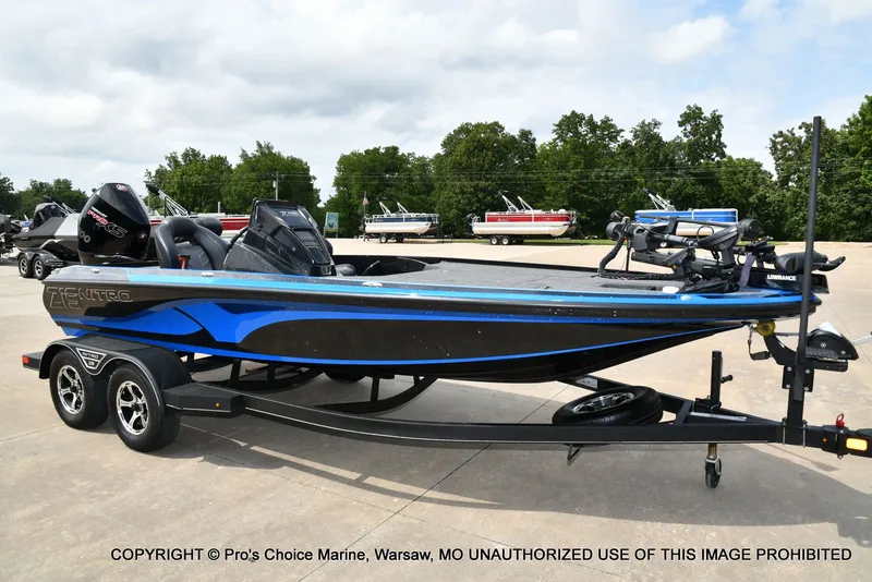 The Image of A 2023 Nitro Z19 Pro boat on a trailer, parked on a concrete lot with trees in the background. - 1