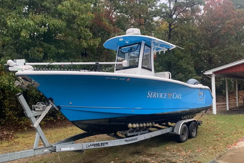 Slide: The Image of 2020 Sea Hunt Ultra 275 SE boat on trailer, blue hull, parked outdoors. - 16