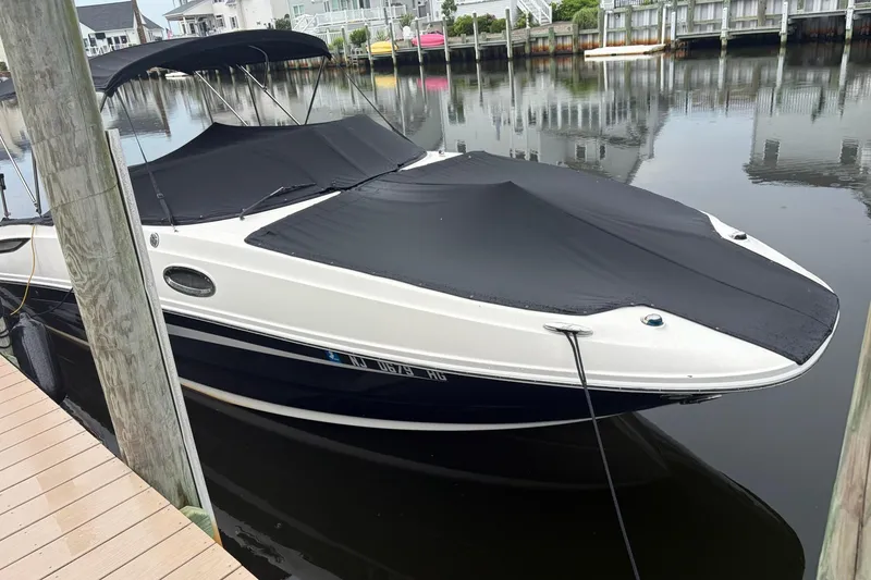 Slide: The Image of 2014 Sea Ray 260 Sundeck boat docked with black covers in a serene marina. - 1