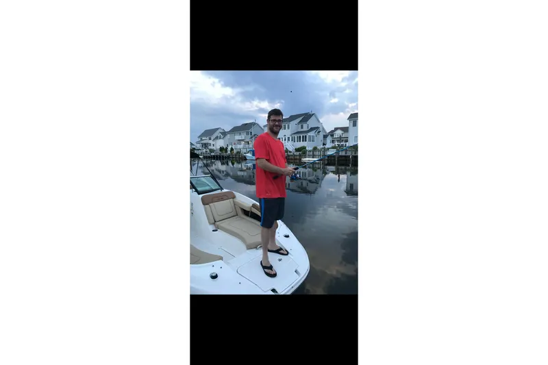 Slide: The Image of Man fishing on a 2014 Sea Ray 260 Sundeck boat near waterfront homes. - 11