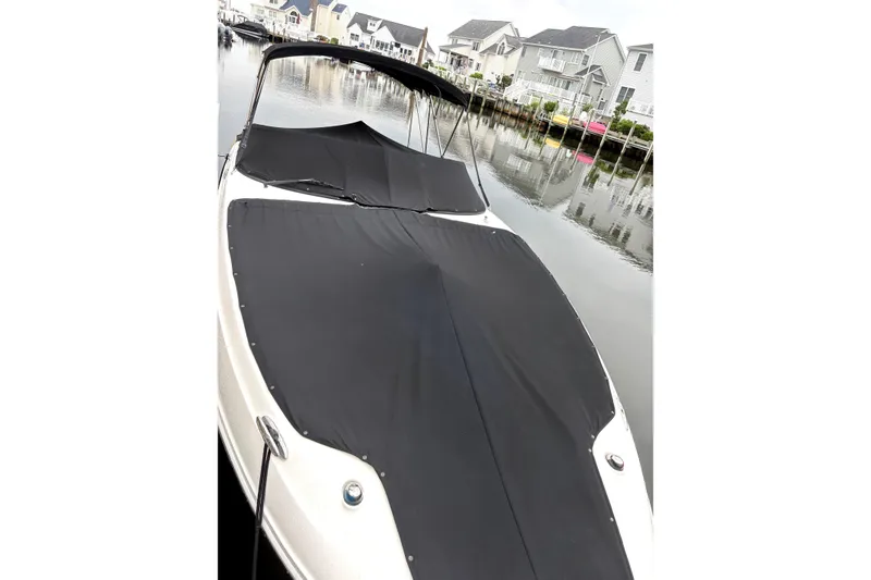 Slide: The Image of 2014 Sea Ray 260 Sundeck boat with black cover, docked near waterfront homes. - 3