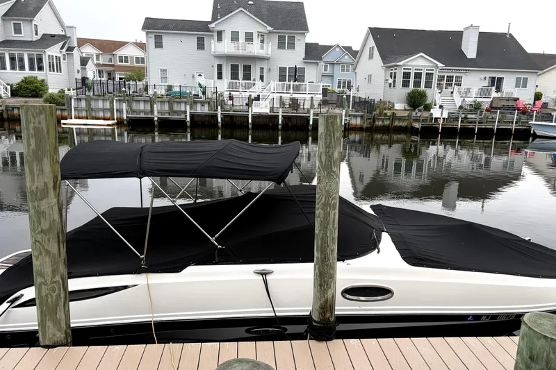 Slide: The Image of 2014 Sea Ray 260 Sundeck docked by waterfront homes, covered with black canopy. - 5