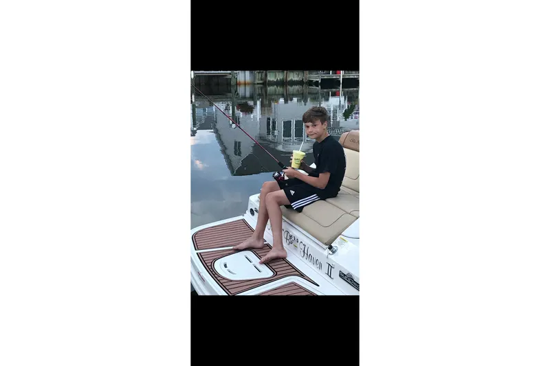 Slide: The Image of Young person relaxing on a 2014 Sea Ray 260 Sundeck, holding a drink by the water. - 9