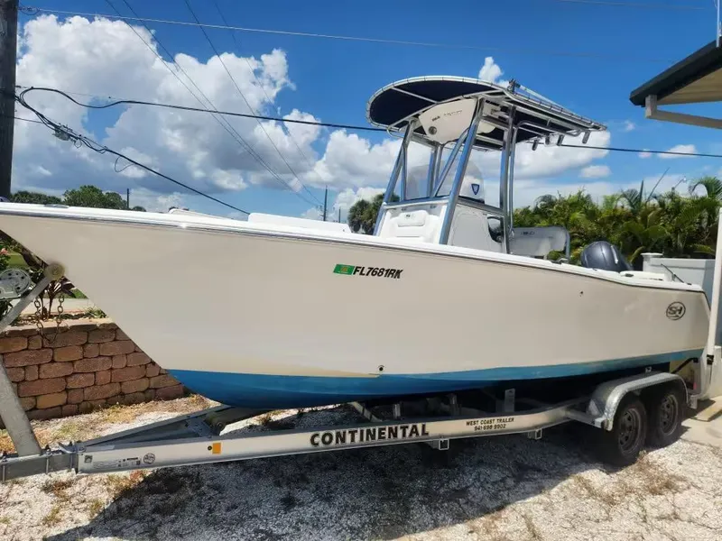 The Image of A white Sea Hunt Ultra 255 SE boat on a trailer, parked under a blue sky. - 1
