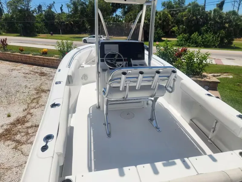 Slide: The Image of The image shows a 2017 Sea Hunt Ultra 255 SE boat. It features a clean, white deck with a helm and seating. Trees and a road are visible in the background. - 5