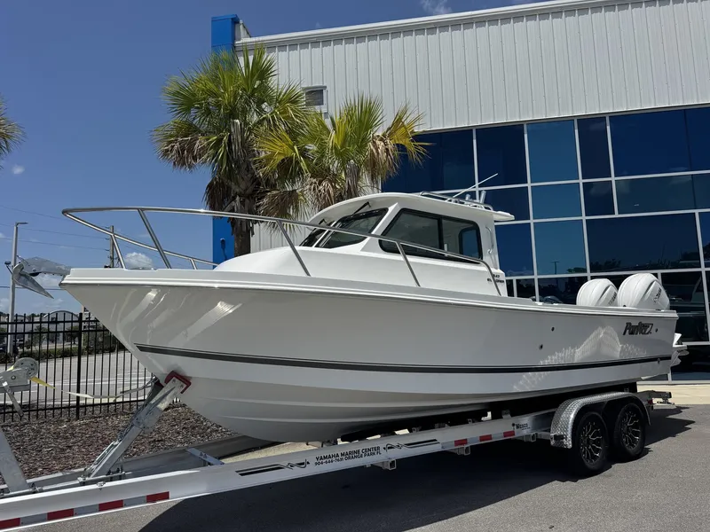 The Image of A white Parker 247 Explorer boat on a trailer in front of a modern building. - 1