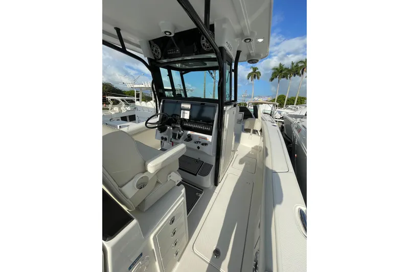 Slide: The Image of 2024 World Cat 325 CC boat interior with modern helm and seating, docked under clear skies. - 4