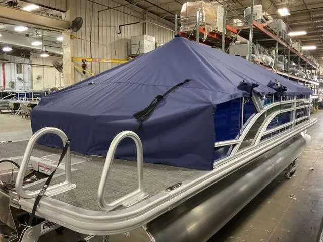 Slide: The Image of A Bennington pontoon boat, model S Swingback 22 SSB, year 2025, with a blue cover in a warehouse. - 15