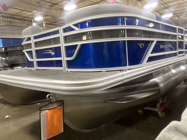 Slide: The Image of A Bennington pontoon boat with a blue hull and silver details is in a warehouse. - 3