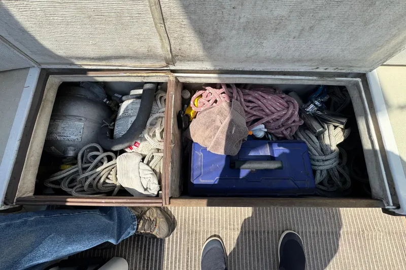 Slide: The Image of An open storage compartment on a boat shows ropes, a blue toolbox, and a gas cylinder. - 45