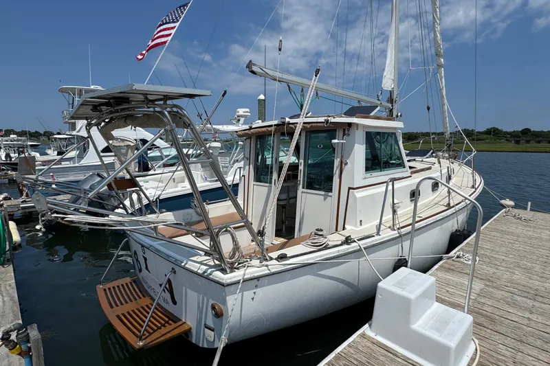 Slide: The Image of 1989 Cape Dory 30 Motorsailer docked, featuring American flag and clear blue sky. - 1