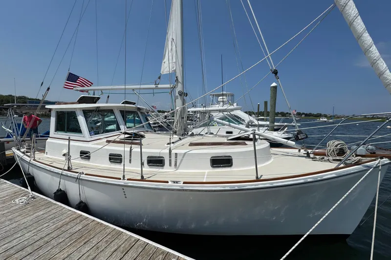 The Image of 1989 Cape Dory 30 Motorsailer docked, featuring classic design and American flag. - 0