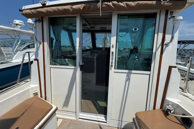 Slide: The Image of 1989 Cape Dory 30 Motorsailer with sliding glass doors and cushioned seating on deck. - 43