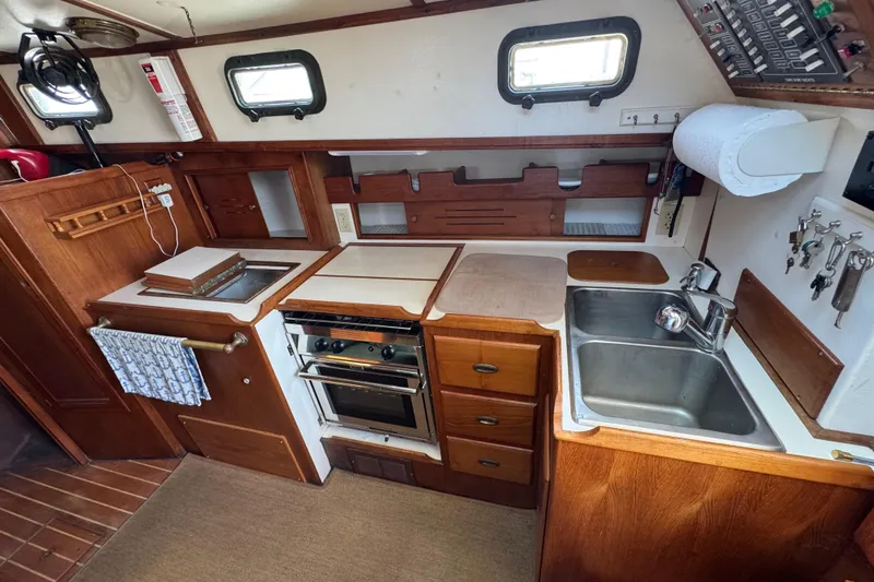 Slide: The Image of Interior of 1989 Cape Dory 30 Motorsailer kitchen with stove, sink, and wooden cabinetry. - 26