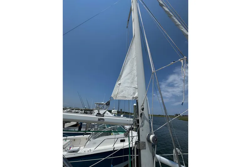Slide: The Image of Cape Dory 30 Motorsailer 1989 with sails raised, docked under clear blue sky. - 10