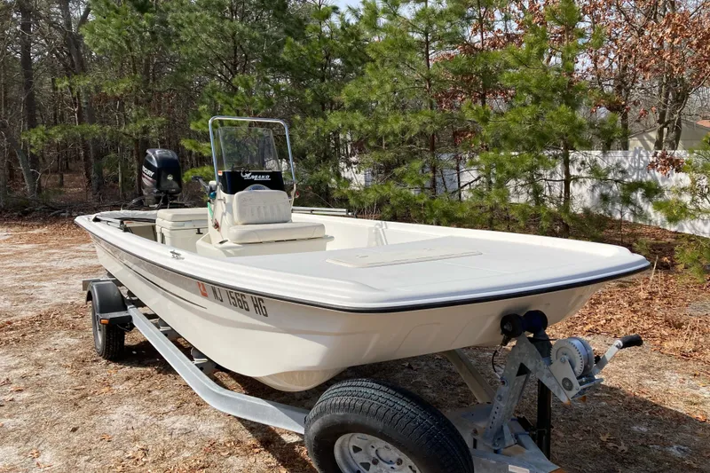 Slide: The Image of 2014 Mako Pro Skiff 17 CC boat on trailer, parked in wooded area. - 3