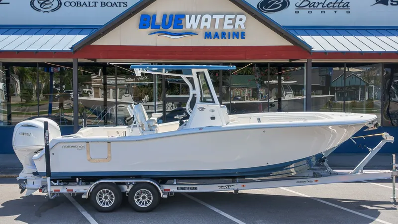 The Image of A 2027 Tidewater 272 CC Adventure boat on a trailer in front of a marine store. - 1