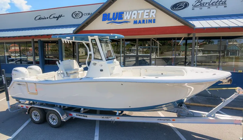 Slide: The Image of A white 2027 Tidewater 272 CC Adventure boat on a trailer in front of a marine store. - 3