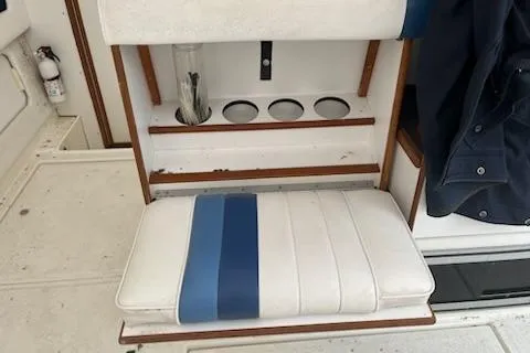 Slide: The Image of 1989 Sea Ray 300 Sundancer boat seat with cup holders and blue-striped cushion. - 10