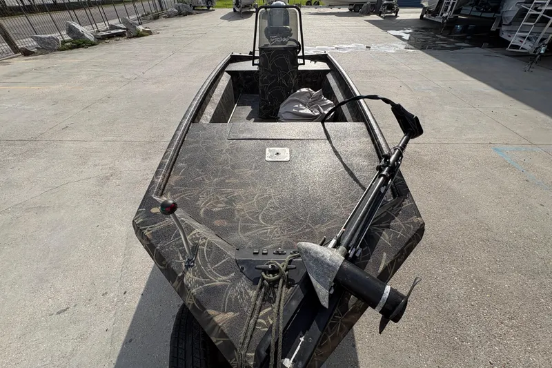 Slide: The Image of 2018 Excel 1854 Shallow Water F4 Console boat with camouflage design, parked outdoors. - 10