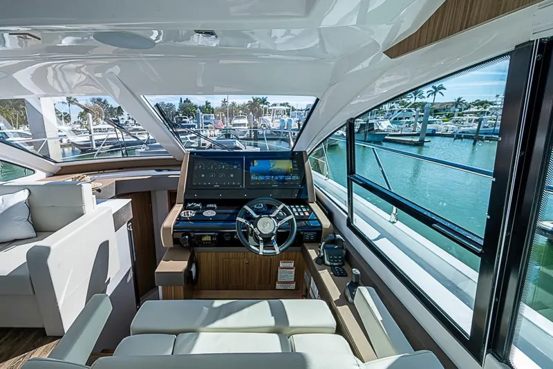 Slide: The Image of Interior view of 2025 Cruisers Yachts 50 Cantius helm with marina backdrop. - 5