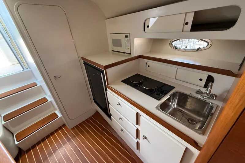 Slide: The Image of Compact galley kitchen in 1995 Tiara Yachts 3100 Open, featuring stove, sink, and microwave. - 24