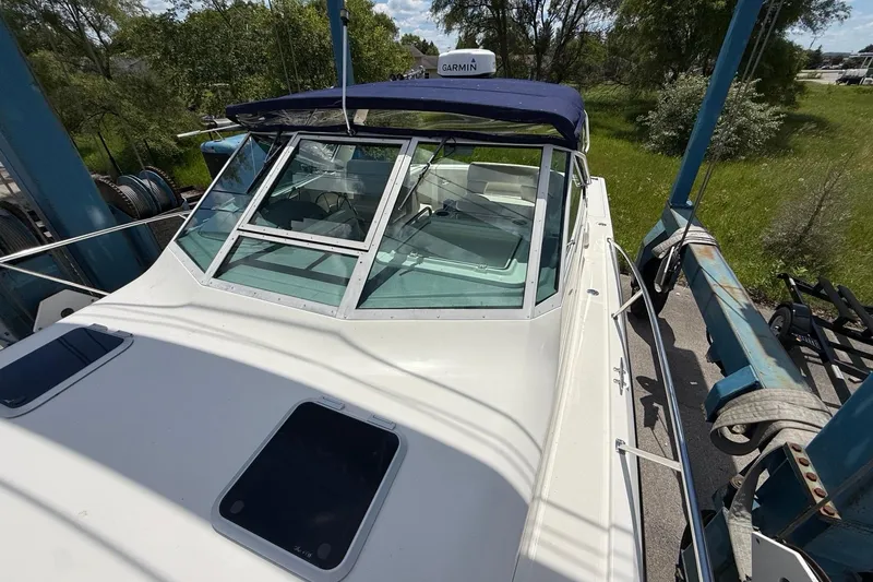 Slide: The Image of 1995 Tiara Yachts 3100 Open boat with blue canopy, docked outdoors. - 11