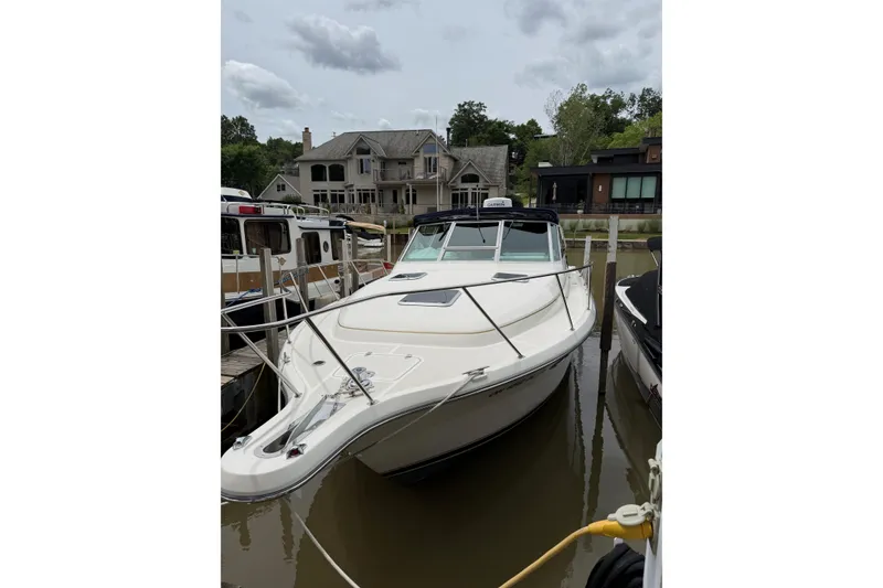 The Image of 1995 Tiara Yachts 3100 Open docked near waterfront homes under cloudy skies. - 0