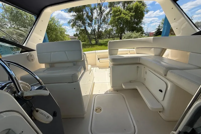 Slide: The Image of 1995 Tiara Yachts 3100 Open interior with white seating and steering wheel, under a sunny sky. - 26