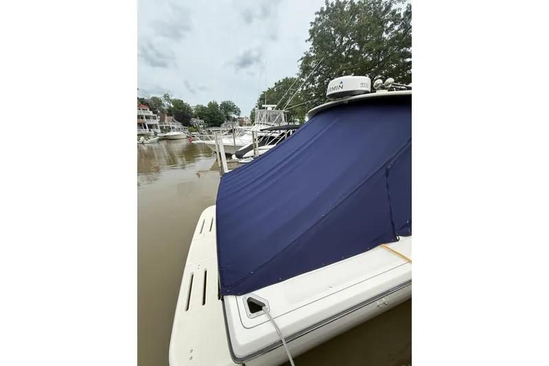 Slide: The Image of 1995 Tiara Yachts 3100 Open docked with blue cover, surrounded by calm waters. - 1