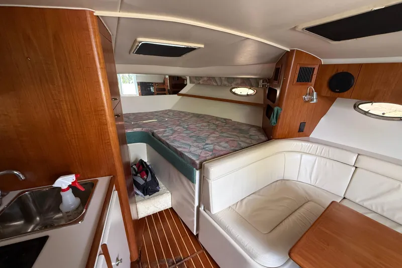 Slide: The Image of Interior of 1995 Tiara Yachts 3100 Open, featuring cozy seating and compact kitchen area. - 22