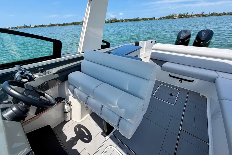 Slide: The Image of 2022 Aviara AV32 OB boat interior with helm, seating, and twin outboard motors on a sunny day. - 32