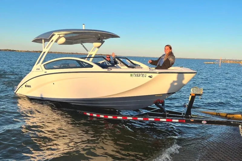 Slide: The Image of 2021 Yamaha Boats 275SD on trailer, two people aboard, near water. - 1