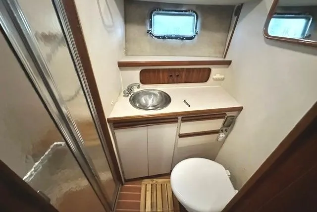 Slide: The Image of 1989 Carver 32 Aft Cabin Motor Yacht bathroom with sink, toilet, and window. - 19