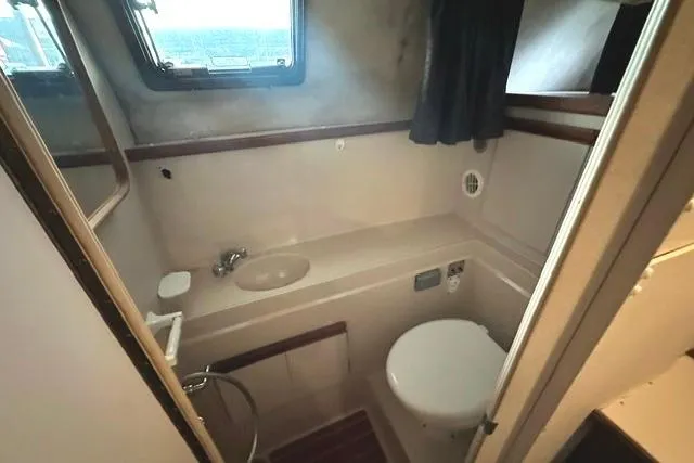 Slide: The Image of 1989 Carver 32 Aft Cabin Motor Yacht bathroom with sink, toilet, and window. - 22