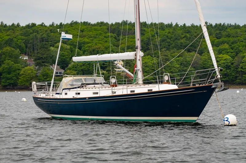 The Image of Sailboat Morris Ocean Series 44, 1992 model, anchored on a calm lake with forested background. - 1