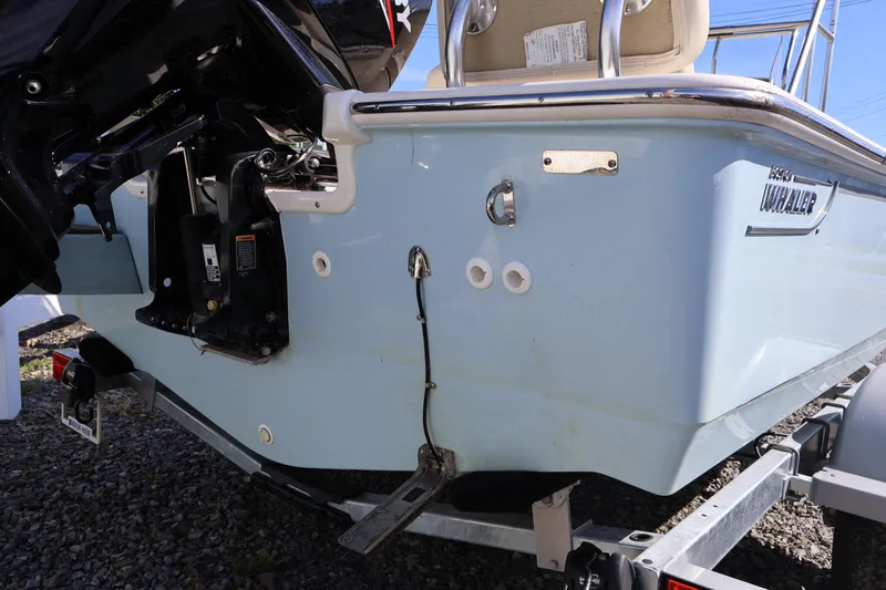 Slide: The Image of 2023 Boston Whaler 170 Montauk boat rear view on trailer, showcasing motor and hull details. - 13
