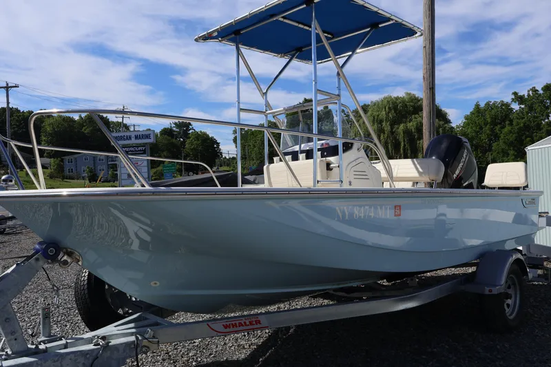 Slide: The Image of 2023 Boston Whaler 170 Montauk boat on trailer, parked outdoors under blue sky. - 2