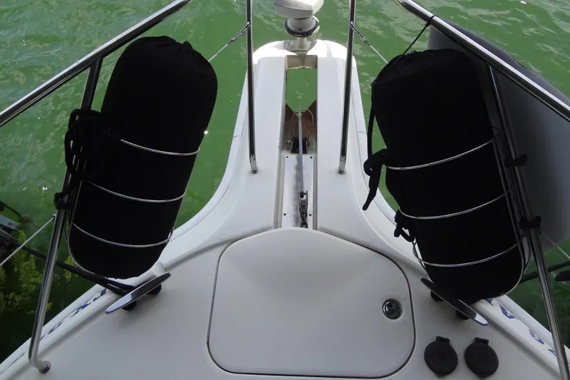 Slide: The Image of Bow view of 2005 Silverton 34 Convertible yacht with black fenders on green water. - 10