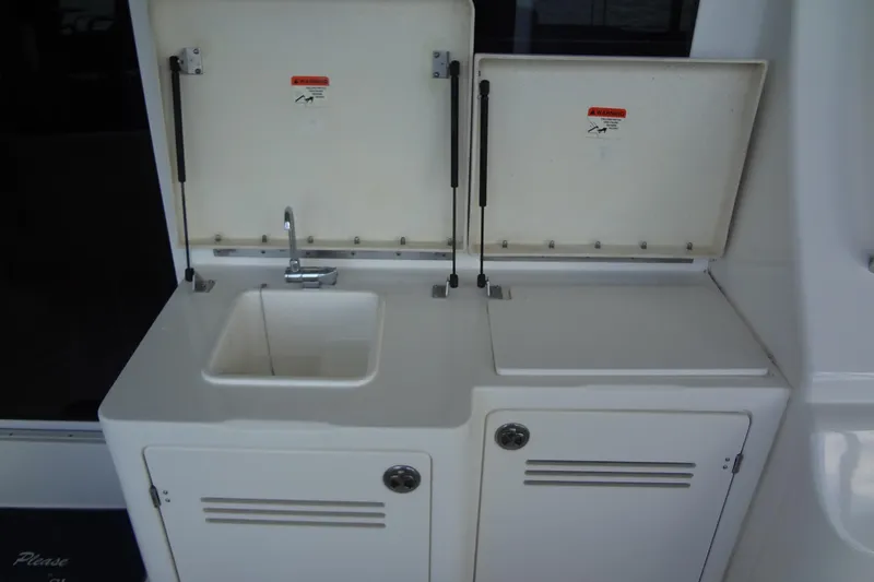 Slide: The Image of 2005 Silverton 34 Convertible yacht sink and storage area with open lids. - 17