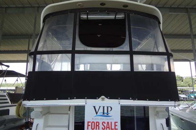 Slide: The Image of 2005 Silverton 34 Convertible yacht for sale, docked under a covered marina. - 2