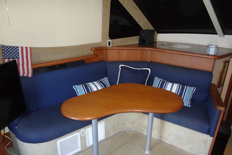 Slide: The Image of Interior of 2005 Silverton 34 Convertible yacht with blue seating and wooden table. - 34