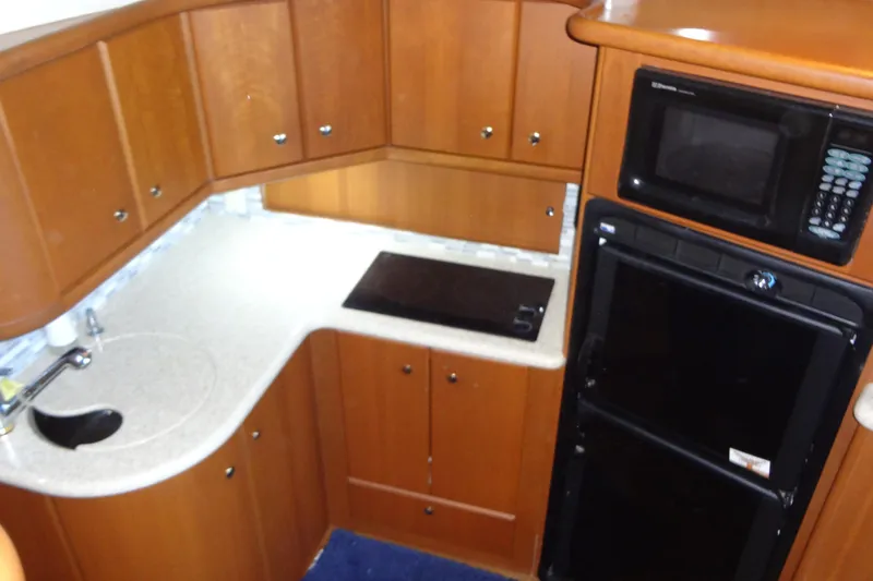 Slide: The Image of 2005 Silverton 34 Convertible yacht kitchen with wood cabinets, microwave, and compact appliances. - 40