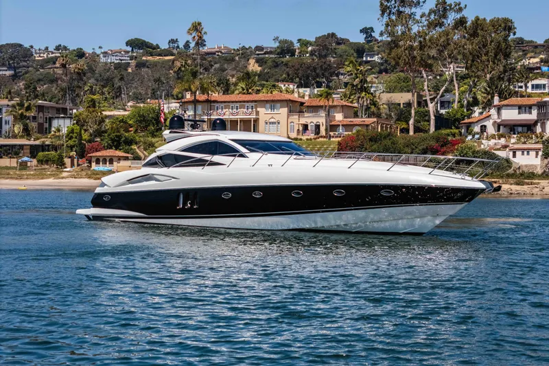 Slide: The Image of 2005 Sunseeker Predator 68 yacht cruising near luxurious waterfront homes. - 2