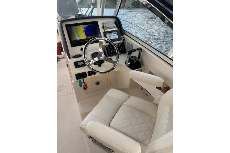 Slide: The Image of 2020 Grady White 275 Freedom boat cockpit with steering wheel and navigation screens. - 16