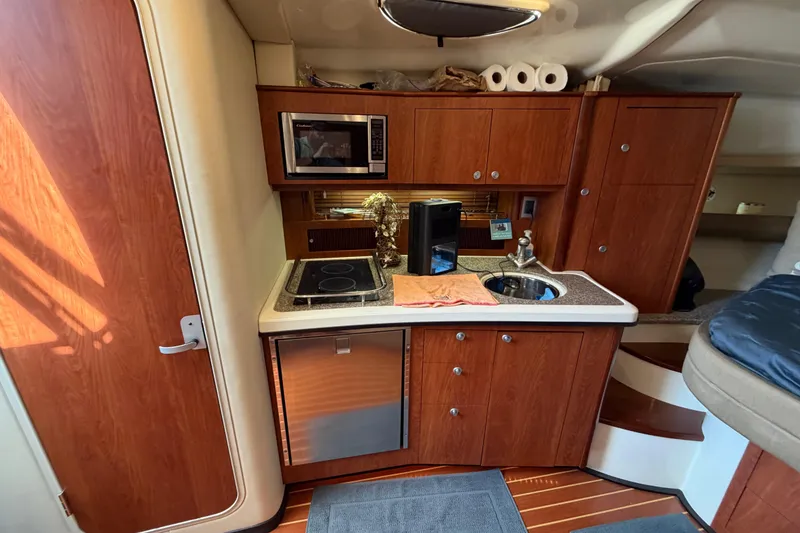 Slide: The Image of 2009 Monterey 340 Sport Yacht interior kitchen with wood cabinets, microwave, and sink. - 29