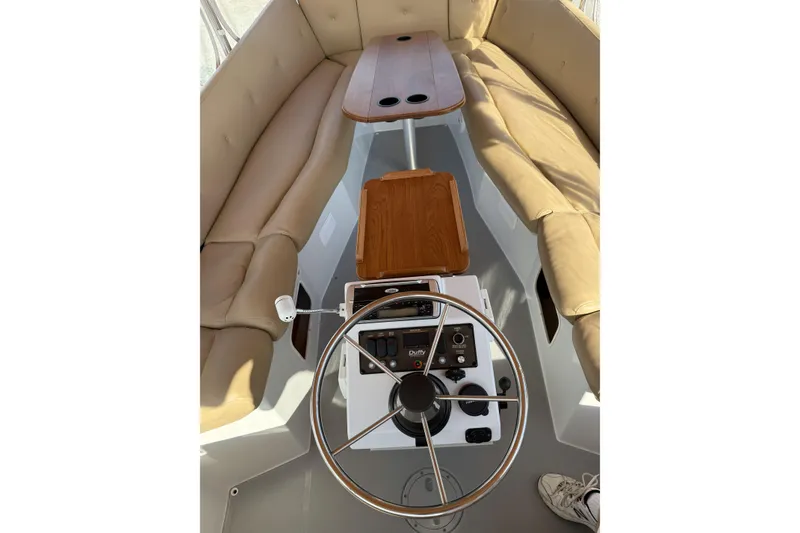 Slide: The Image of 2004 Duffy 21 Classic boat interior with steering wheel, beige seating, and wooden tables. - 9
