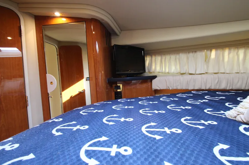 Slide: The Image of Interior of 2000 Sea Ray 410 Express Cruiser with anchor-patterned bedding and wood finish. - 36