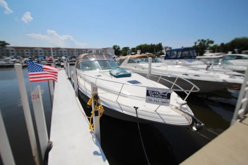 The Image of 2000 Sea Ray 410 Express Cruiser docked at marina with American flag. - 0