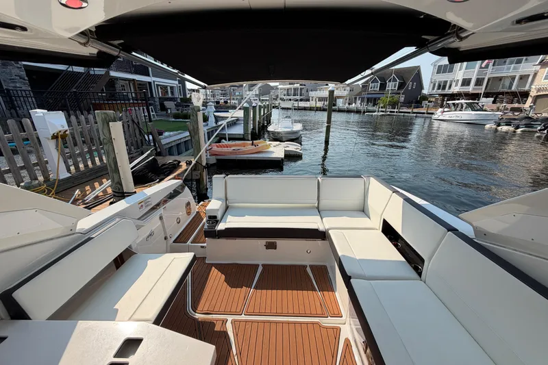Slide: The Image of 2017 Monterey 378SE Super Express boat interior with white seating and wooden flooring at a marina. - 10